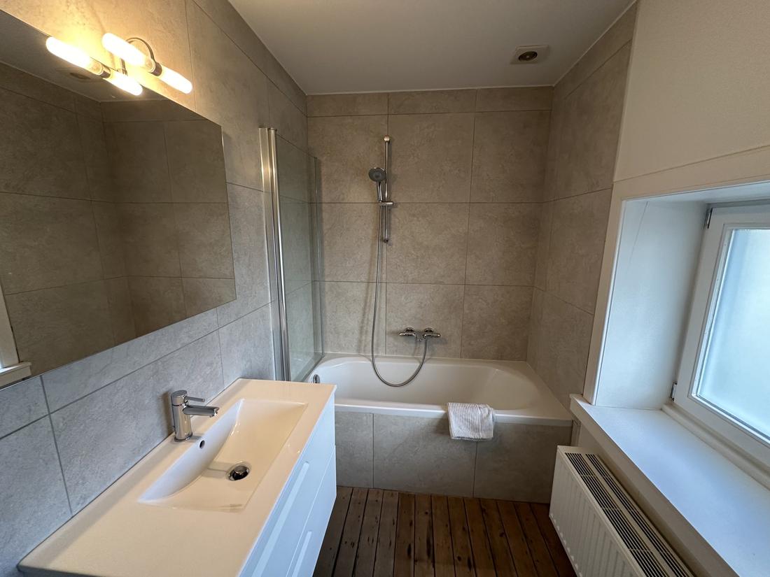 Badkamer met ligbad, douche en betegelde muren.