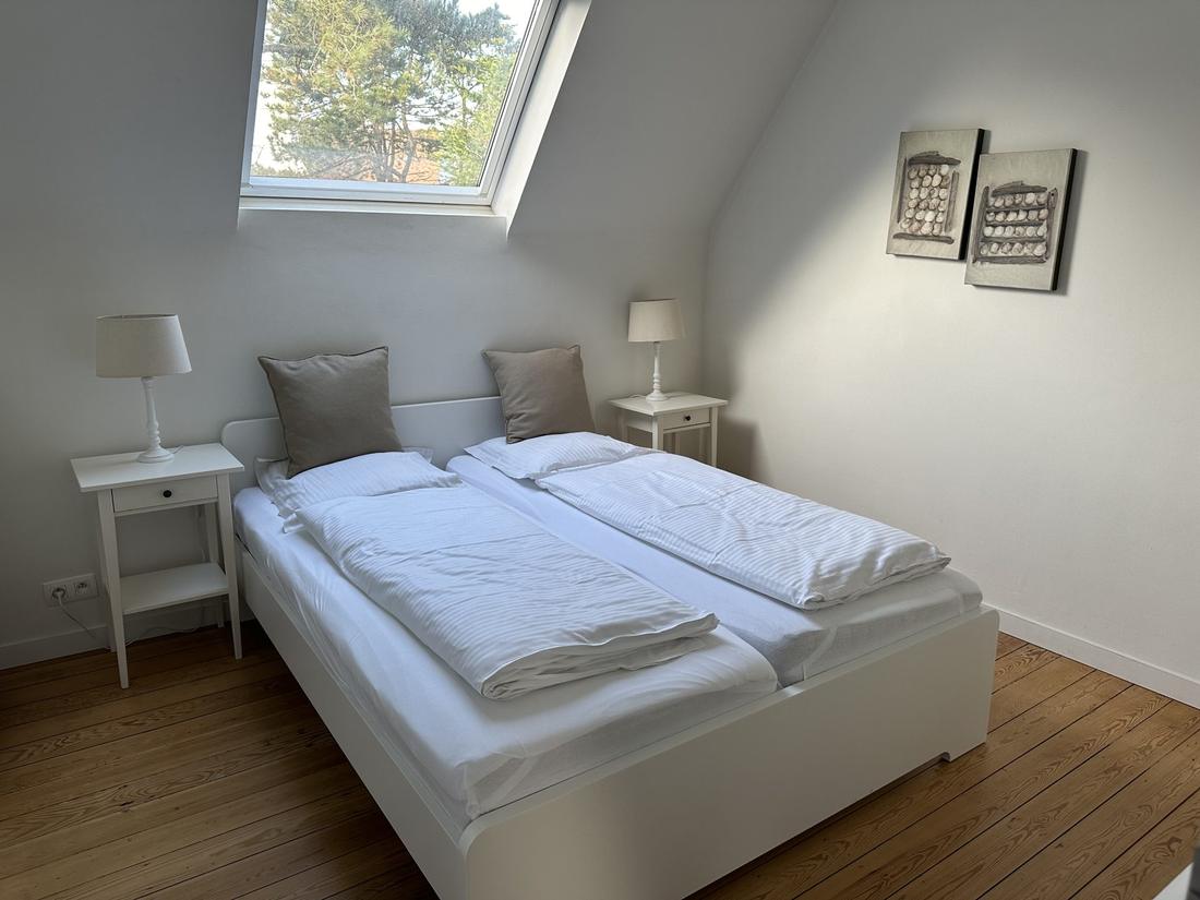 Slaapkamer 2, met twee bedden tegen elkaar onder een hellend dakraam.