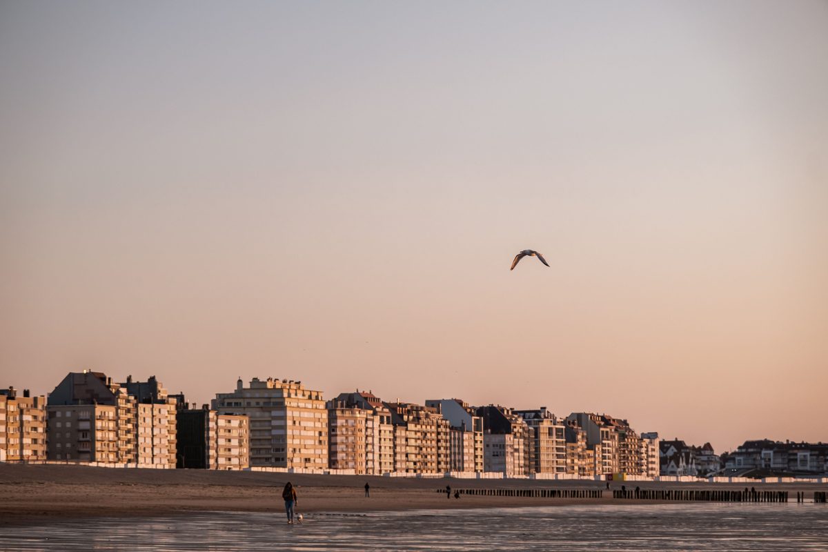 De Haan aan Zee bij zonsondergang, met de karakteristieke belle-&eacute;poquegevels aan de zeedijk.