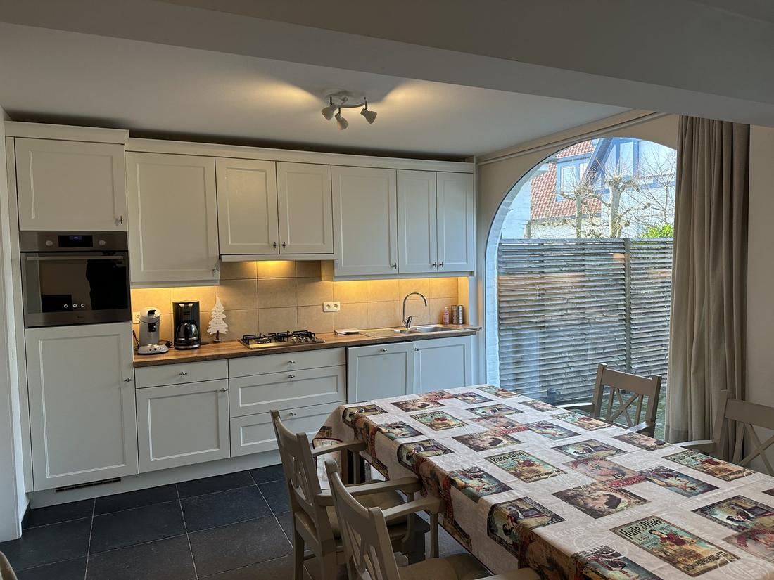 Landelijke keuken en eettafel, met crèmekleurige kasten en een gewelfde tuindeur.